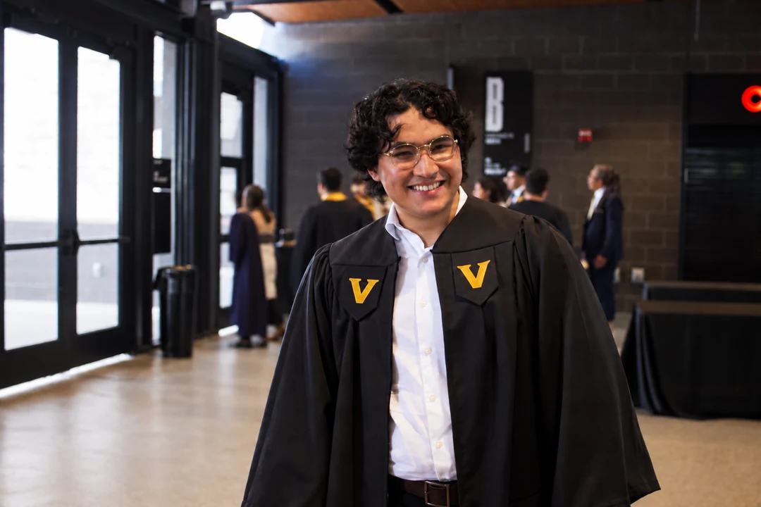 Amir smiling in his graduation gown.